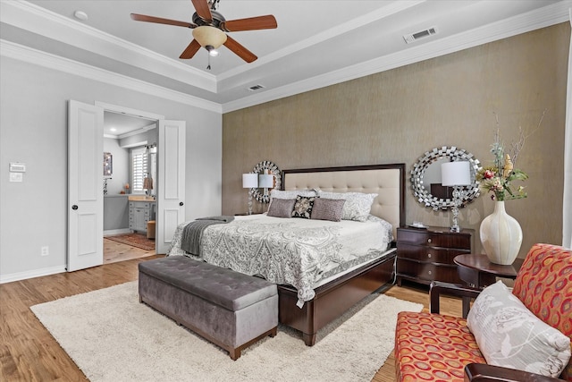 bedroom featuring wood finished floors, baseboards, crown molding, connected bathroom, and a ceiling fan