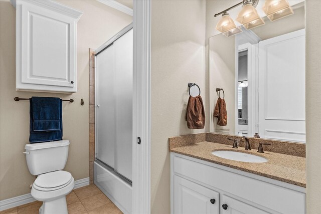 full bath with tile patterned floors, toilet, vanity, shower / bath combination with glass door, and baseboards