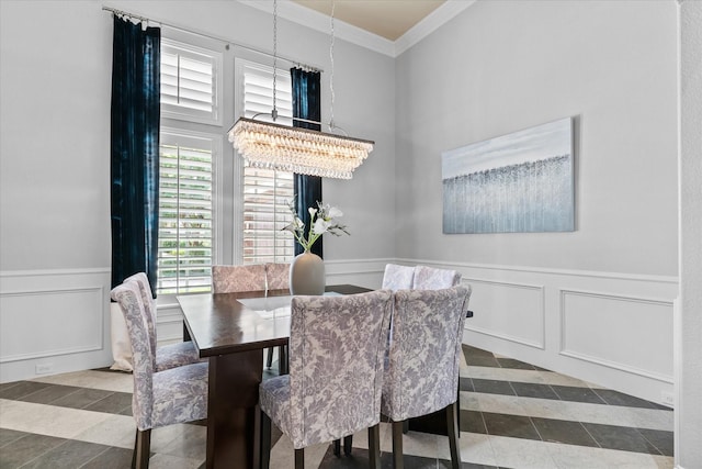 dining space with ornamental molding, a decorative wall, a chandelier, a wainscoted wall, and tile patterned floors