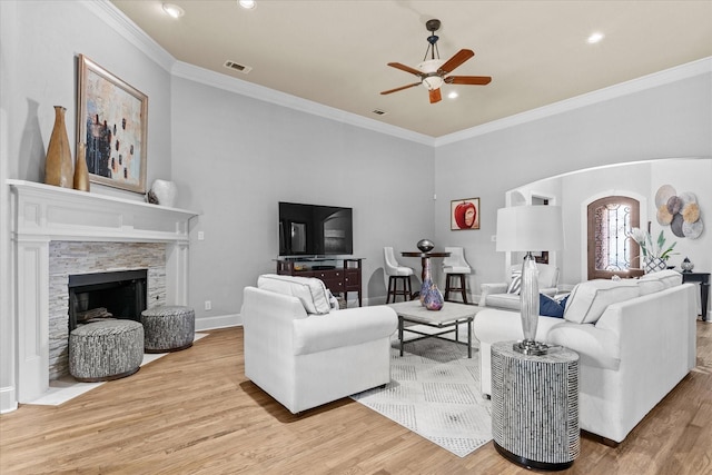 living room with a ceiling fan, wood finished floors, crown molding, a fireplace, and recessed lighting