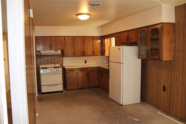 114 Wilmington Ave, Waxahachie, TX 75165 - kitchen featuring white appliances, brown cabinets, concrete flooring, light countertops, and glass insert cabinets