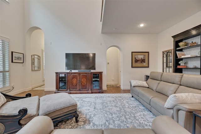 7320 San Saba Dr, Mckinney, TX 75070 - living room featuring arched walkways, wood finished floors, a towering ceiling, and recessed lighting
