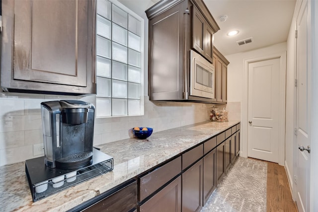 7320 San Saba Dr, Mckinney, TX 75070 - kitchen with stainless steel microwave, tasteful backsplash, light wood-style flooring, light stone countertops, and recessed lighting