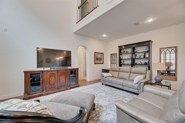7320 San Saba Dr, Mckinney, TX 75070 - living area featuring arched walkways, wood finished floors, a towering ceiling, and recessed lighting