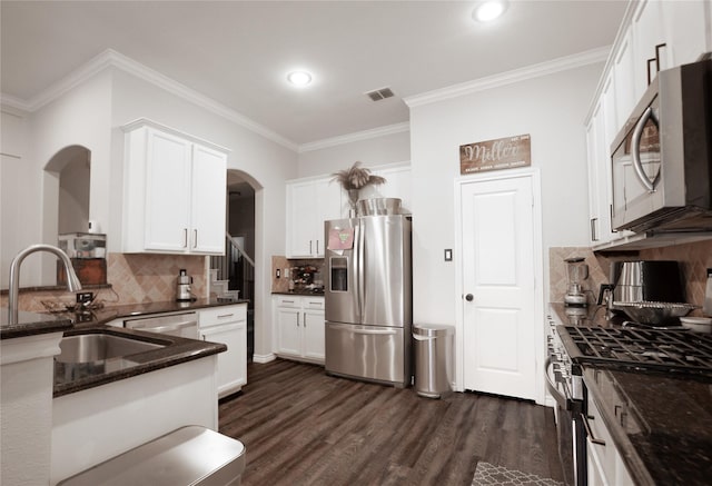4804 Spicewood Ln, Arlington, TX 76017 - kitchen featuring appliances with stainless steel finishes, arched walkways, a sink, dark wood-type flooring, and tasteful backsplash