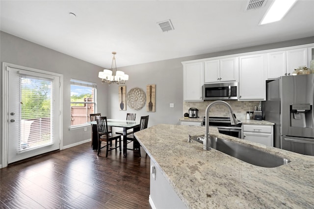 3421 Paisano Trl, Plano, TX 75093 - kitchen featuring appliances with stainless steel finishes, a sink, a chandelier, white cabinetry, and decorative backsplash