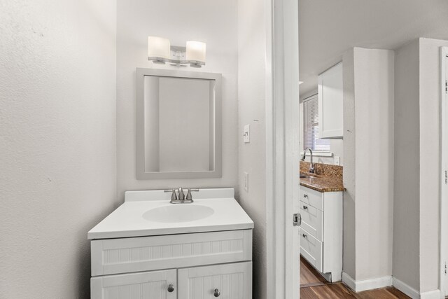 531 Norwood Cir E, Arlington, TX 76013 - bathroom featuring two vanities, wood finished floors, and baseboards
