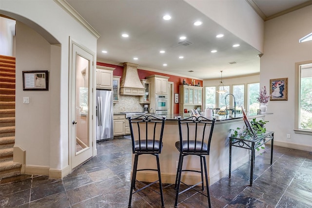 6700 Lions Gate Ct, Arlington, TX 76001 - kitchen with stainless steel appliances, custom range hood, baseboards, a breakfast bar area, and recessed lighting