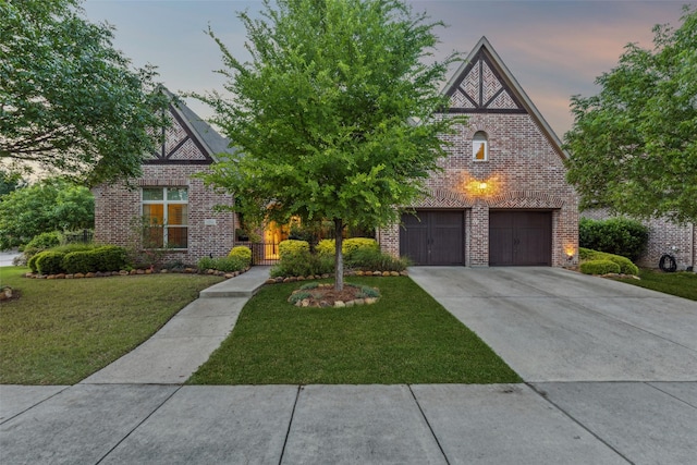english style home with a front lawn, brick siding, and concrete driveway