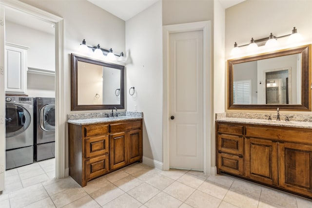 full bathroom featuring independent washer and dryer, two vanities, tile patterned flooring, and baseboards