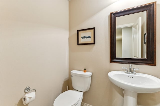 bathroom with toilet, a sink, and baseboards