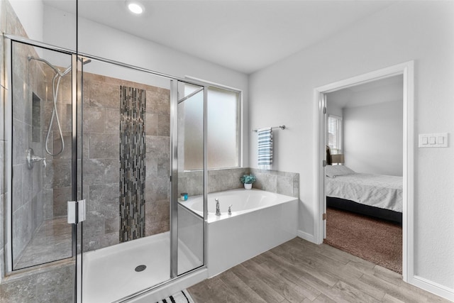 full bathroom featuring wood finished floors, a stall shower, a bath, and ensuite bathroom
