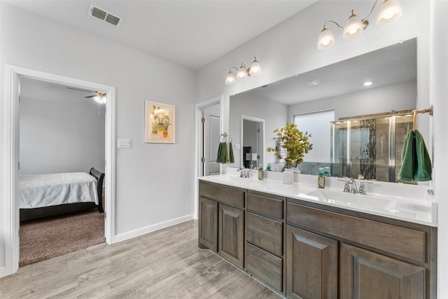 bathroom featuring wood finished floors, a shower stall, double vanity, ceiling fan, and ensuite bathroom