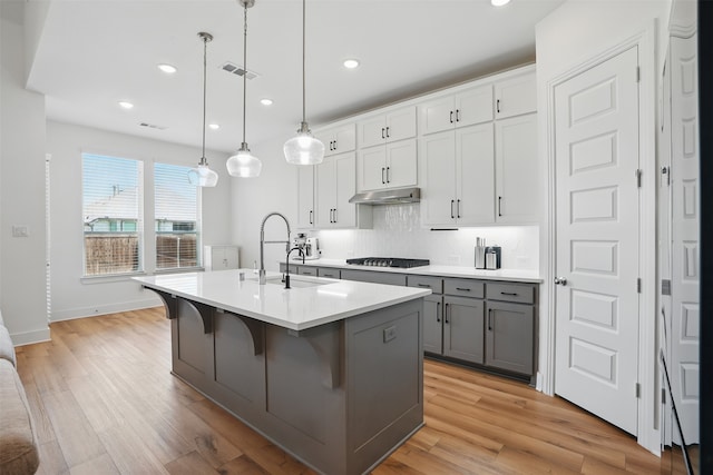 4008 Prickly Pear Ave, Aubrey, TX 76227 - kitchen featuring gray cabinets, under cabinet range hood, a sink, gas stovetop, and an island with sink