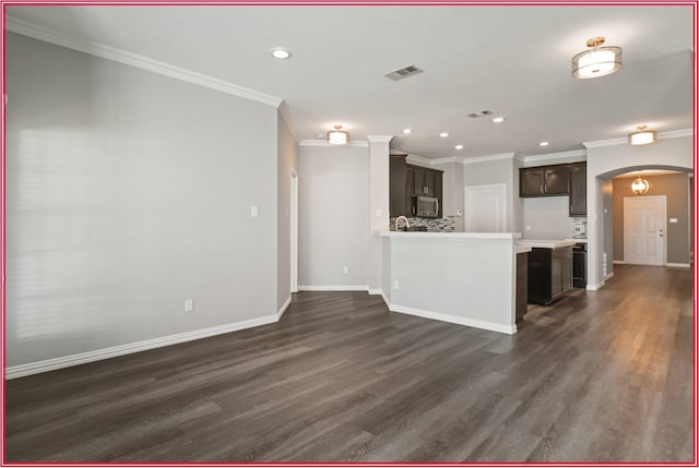 5005 Odeum Ct, Fort Worth, TX 76244 - kitchen with stainless steel microwave, arched walkways, ornamental molding, tasteful backsplash, and dark wood-type flooring