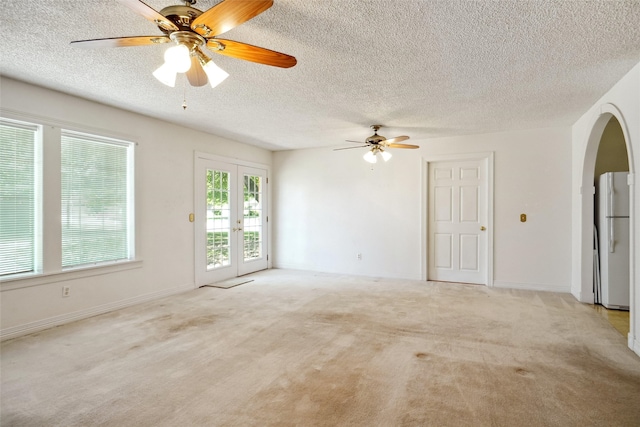 1508 Raborn Dr, Bowie, TX 76230 - spare room featuring a textured ceiling, arched walkways, french doors, carpet floors, and ceiling fan
