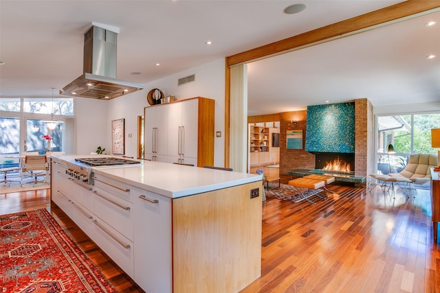 5848 Colhurst St, Dallas, TX 75230 - kitchen featuring island exhaust hood, healthy amount of natural light, a brick fireplace, and stainless steel gas stovetop