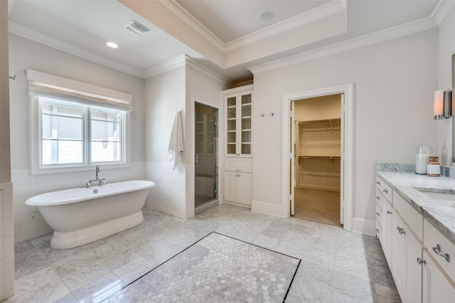 full bath with a shower stall, vanity, a spacious closet, crown molding, and a freestanding bath