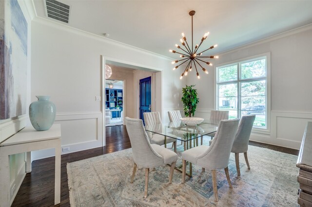 dining area featuring a chandelier, ornamental molding, a decorative wall, a wainscoted wall, and dark wood-style floors