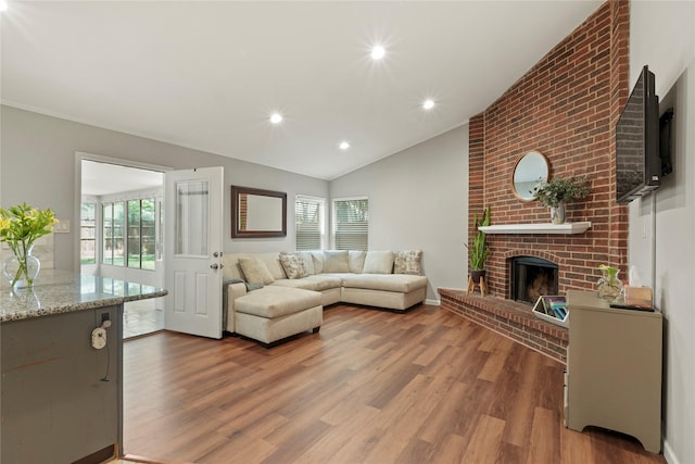 living area featuring a fireplace, vaulted ceiling, healthy amount of natural light, wood finished floors, and recessed lighting