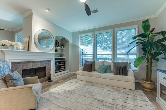 2505 Hillary Trl, Mansfield, TX 76063 - living area with a tiled fireplace, a ceiling fan, wood finished floors, and ornamental molding