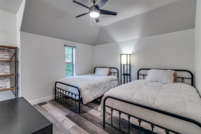 bedroom featuring wood finished floors, vaulted ceiling, baseboards, and a ceiling fan