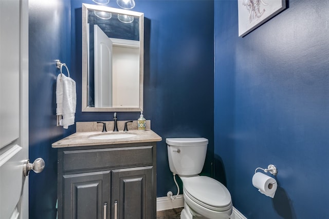 bathroom with toilet, baseboards, and vanity