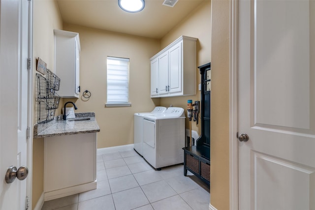 clothes washing area with washing machine and dryer, cabinet space, light tile patterned flooring, and baseboards