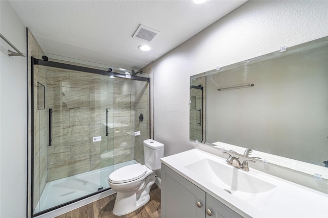 3809 Glengate Dr, Arlington, TX 76016 - bathroom with wood finished floors, toilet, vanity, a shower stall, and a textured ceiling