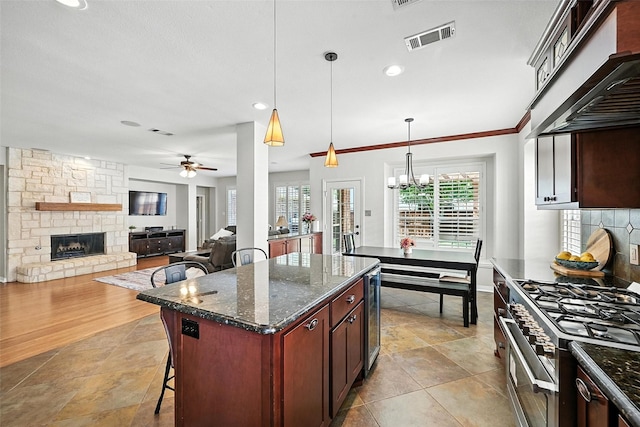 2726 Bandolier Ln, Frisco, TX 75033 - kitchen with a stone fireplace, ceiling fan, high end stove, wine cooler, and a breakfast bar area
