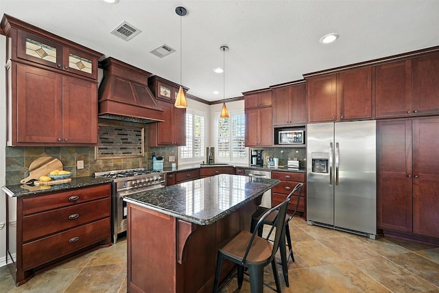 2726 Bandolier Ln, Frisco, TX 75033 - kitchen featuring stainless steel appliances, custom exhaust hood, a kitchen island, decorative backsplash, and dark stone countertops