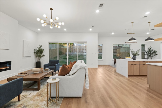 426 Avenue Ave E, Dallas, TX 75203 - living room with recessed lighting, light wood-style floors, a glass covered fireplace, a chandelier, and baseboards