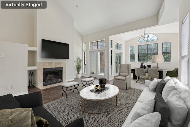 living area with a chandelier, wood finished floors, high vaulted ceiling, a tiled fireplace, and built in features