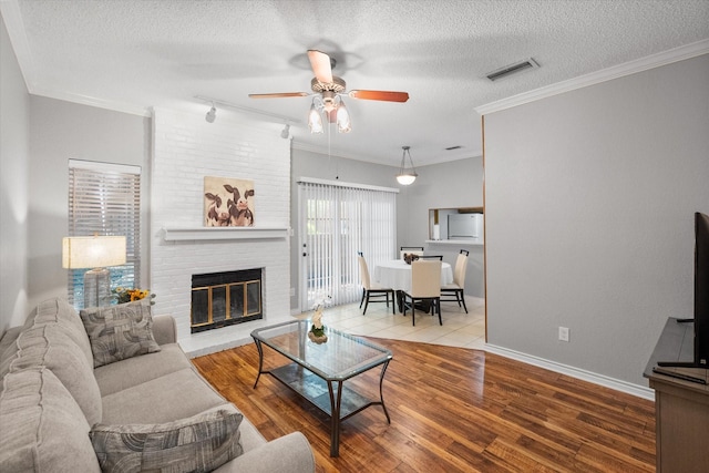2101 Saint Michaels Dr Unit 109, Arlington, TX 76011 - living room with a ceiling fan, wood finished floors, a brick fireplace, a textured ceiling, and baseboards