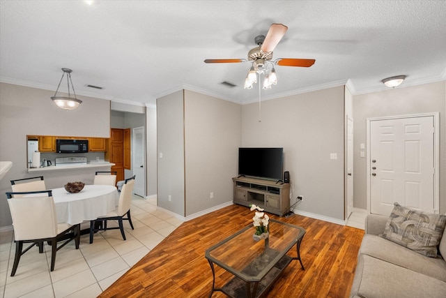 2101 Saint Michaels Dr Unit 109, Arlington, TX 76011 - living room with ceiling fan, crown molding, baseboards, light tile patterned floors, and a textured ceiling