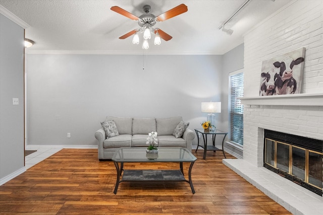 2101 Saint Michaels Dr Unit 109, Arlington, TX 76011 - living area featuring ceiling fan, wood finished floors, a textured ceiling, ornamental molding, and a brick fireplace