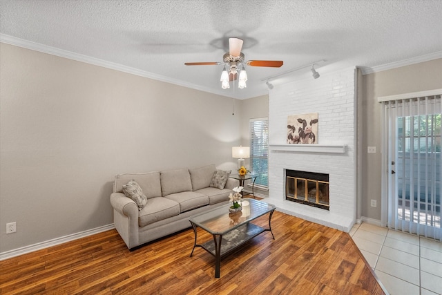 2101 Saint Michaels Dr Unit 109, Arlington, TX 76011 - living area with rail lighting, ceiling fan, a textured ceiling, wood finished floors, and a fireplace