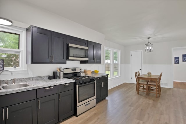 610 Phillips St, Cleburne, TX 76033 - kitchen with appliances with stainless steel finishes, a sink, light wood-style flooring, and a wainscoted wall