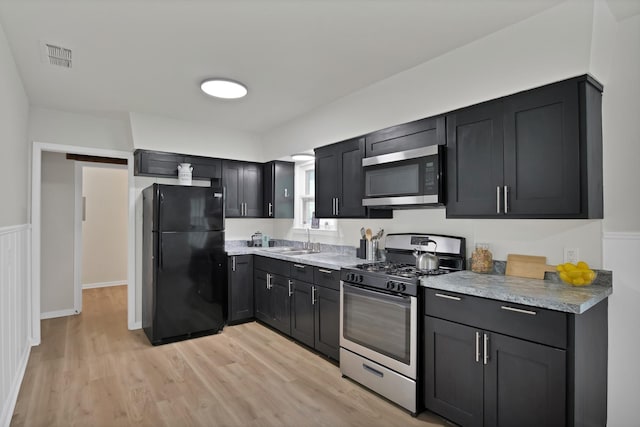 610 Phillips St, Cleburne, TX 76033 - kitchen with stainless steel appliances, a sink, light wood finished floors, light countertops, and dark cabinetry