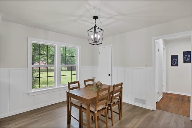 610 Phillips St, Cleburne, TX 76033 - dining space with a chandelier, wood finished floors, a wainscoted wall, and a decorative wall