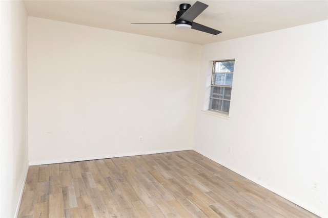 spare room with a ceiling fan, light wood finished floors, and baseboards