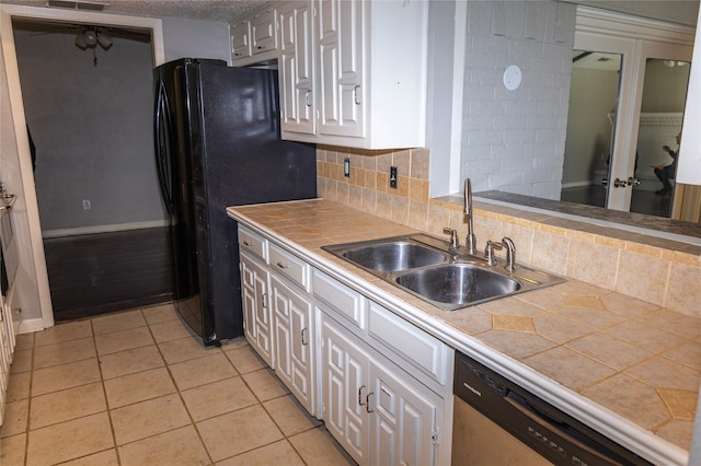 kitchen with stainless steel dishwasher, a sink, white cabinetry, tile counters, and light tile patterned floors