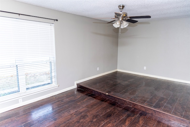 empty room featuring ceiling fan, dark wood-type flooring, a textured ceiling, and baseboards