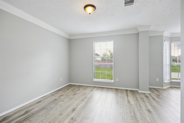spare room with healthy amount of natural light, light wood-type flooring, crown molding, baseboards, and a textured ceiling