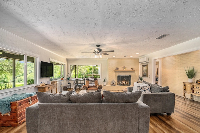 4151 Oakcrest Ln, Fort Worth, TX 76126 - living area featuring a wall mounted AC, a textured ceiling, wood finished floors, ceiling fan, and a brick fireplace