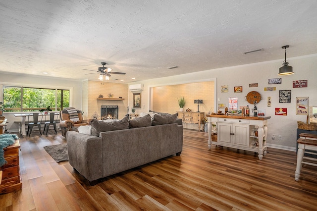 4151 Oakcrest Ln, Fort Worth, TX 76126 - living area featuring a wall unit AC, a ceiling fan, a textured ceiling, dark wood finished floors, and a brick fireplace