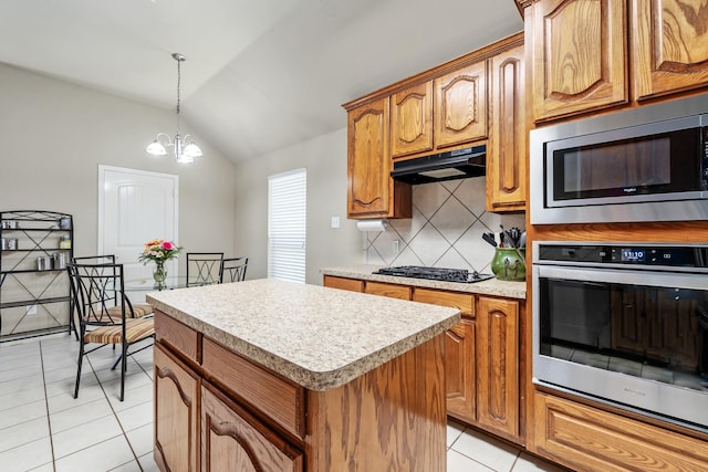3601 Carmel Mountain Dr, Mckinney, TX 75070 - kitchen featuring stainless steel appliances, under cabinet range hood, light tile patterned flooring, vaulted ceiling, and a kitchen island