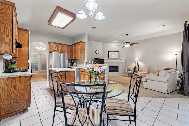 3601 Carmel Mountain Dr, Mckinney, TX 75070 - dining space featuring light tile patterned floors, a ceiling fan, a fireplace, and a chandelier