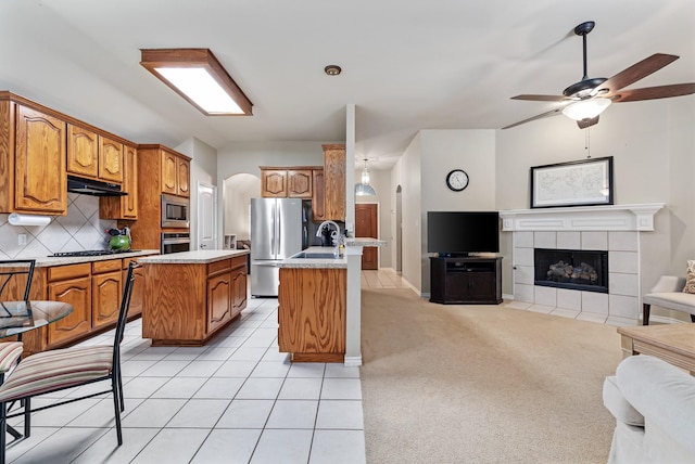 3601 Carmel Mountain Dr, Mckinney, TX 75070 - kitchen with open floor plan, appliances with stainless steel finishes, under cabinet range hood, arched walkways, and brown cabinets