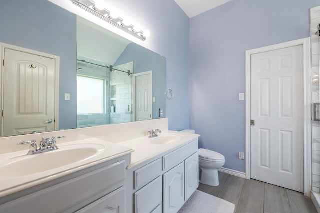 3601 Carmel Mountain Dr, Mckinney, TX 75070 - bathroom with tiled shower, double vanity, wood finished floors, toilet, and baseboards